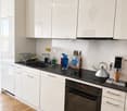 Kitchen. Modern kitchen with white cabinets, black countertops, stainless steel appliances, and various kitchen items on the counter.