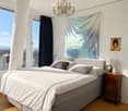 Bedroom. Modern bedroom with a large bed, nightstand, lamp, chandelier, and large windows offering a scenic view.