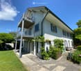 Two-story house with white exterior, balcony, and well-maintained garden.