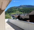 Balcony with tiled floor, white railing, and a scenic mountain view in the background.