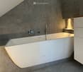 modern bathroom with a large bathtub, gray tiled walls, white floor, white cabinet, silver faucets