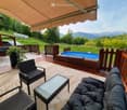 Outdoor patio with a swimming pool, lounge chairs, a coffee table, and a scenic mountain view.