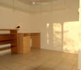 Empty room with tiled floor, white walls, built-in shelves, a small desk, and a lamp.