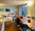 A modern living and dining area with a sofa, coffee table, dining table, chairs, and decorative items.