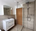 Modern bathroom with a white sink, mirror cabinet, glass-enclosed shower, and modern fixtures.