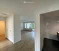 Empty room with wooden flooring, white walls, and built-in closet. Adjacent bathroom with tiled walls and fixtures visible.