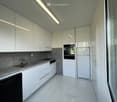 Modern, minimalist kitchen with white cabinets, stainless steel appliances, and a clean, organized layout.