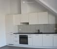 Modern kitchen with white cabinets, black countertop, built-in oven, and stainless steel sink.