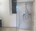 Modern bathroom with a glass-enclosed shower area, marble tiles, and a sleek chrome showerhead.