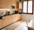 Modern kitchen with light wood cabinets, stainless steel appliances, and a dining area with a table and chairs.