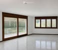 Empty room with white walls, polished tile floor, large sliding glass doors with blinds, and a window with blinds.