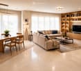 Modern living and dining area with a beige sofa, coffee table, dining table with chairs, bookshelf, TV, and decorative plants.