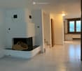 Modern hallway with tiled flooring, white walls, a built-in fireplace with a woven basket on the mantel, and a wooden door leading to another room.