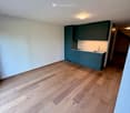 Empty kitchen with light blue cabinets, white countertops, and wooden flooring.