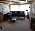 Living room with a dark sectional sofa, coffee table with a "HOME" sign, a cat tree, a fish tank, and a cabinet with decorative items.