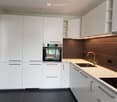 modern kitchen with white cabinets, black tiled floor, integrated oven, sink, faucet, countertop