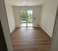 Empty room with wooden floors, white walls, sliding glass doors leading to a terrace