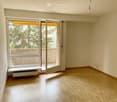 Empty room with wooden flooring, large windows, and an open door leading to a balcony.