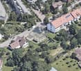 Building. Aerial view of a residential area with multiple houses, solar panels on rooftops, and surrounding greenery.