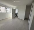 Empty hallway with tiled floor, white walls, and a door leading to a small bathroom with a toilet and sink.