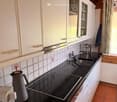 Modern kitchen with white cabinets, black countertops, electric stove, sink, and various appliances.