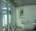 Modern bathroom with a large, freestanding bathtub, sleek white walls, and large glass doors leading to an outdoor area.