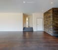 Open living area with a staircase, brick accent wall, tiled flooring, white walls, doorway, metal shelves
