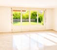 Empty room with light-colored tiled flooring and large sliding glass doors leading to a garden area.