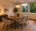 Elegant dining room with a wooden dining table set for six, surrounded by modern chairs, a pendant light, and a sideboard with decorative items and a vase of flowers. Large windows offer a view of greenery outside.
