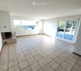 Empty room with tiled floor, large windows, sliding glass door leading to outdoor area, and a small built-in bench with a fireplace.