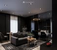 Modern living room with black furniture and beige wooden floor, large grey sofa, round wooden coffee table, potted plants, floor lamp, carpet, and round mirror.