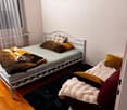 Cozy bedroom with a single bed, pillows, a blanket, and a fluffy rug on the floor.