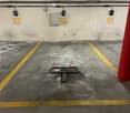 Underground parking area with numbered spots, yellow lines, and a red pillar. No vehicles present.
