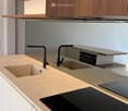 {"visible_features": [], "type": "Kitchen", "objects": ["sink", "faucet", "cabinet", "countertop", "induction cooktop", "cabinet", "cabinet", "cabinet", "cabinet", "cabinet", "cabinet", "cabinet", "cabinet", "cabinet", "cabinet", "cabinet", "cabinet", "ca