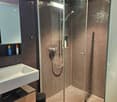 Bathroom. Modern bathroom with a white sink, wooden vanity, glass-enclosed shower, and tiled walls.
