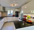 Modern kitchen with white cabinets, black countertops, stainless steel appliances, and a red stand mixer on the island.