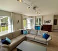 Modern living room with large windows, cream-colored sectional sofa, decorative pillows, coffee table, side table, and cabinet.