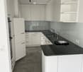 Modern kitchen with white cabinets, black countertops, and stainless steel sink and faucet.