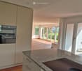 Modern kitchen with granite countertop, induction cooktop, built-in oven, and light-colored cabinets.