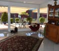 Bright living room with large glass doors leading to a balcony, featuring a red sofa with stuffed animals, a wooden cabinet, a patterned rug, and decorative vases.