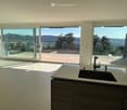 Modern kitchen with large windows offering a scenic view, featuring a sink and faucet.