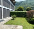 Well-maintained garden with neatly trimmed hedges, small trees, and a view of green hills in the background.