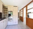 Modern kitchen with light wood cabinets, stainless steel oven, granite countertop, and tiled floor.