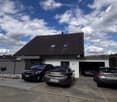 Two-story house with a garage and three parked cars in front.