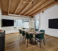 modern meeting room with wooden floor, wooden table, green chairs, TV, blackboard, artwork, and a basket of fruits