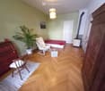 Furnished Room. Cozy, well-furnished room with wooden flooring, a bed, a chair, a small table, a plant, and a wardrobe.