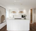 Modern kitchen with white cabinets, a central island, pendant lights, a wine rack, and a vase on the island.