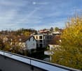 balcony with metal railings, view of neighborhood with houses and trees, blue sky with clouds