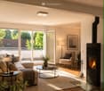Modern living room with a fireplace, large windows offering a view, a beige sofa, a coffee table, an armchair, and decorative items.