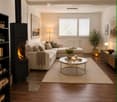 Modern living room with a sectional sofa, coffee table, fireplace, floor lamp, side table, bookshelf, and decorative plant.